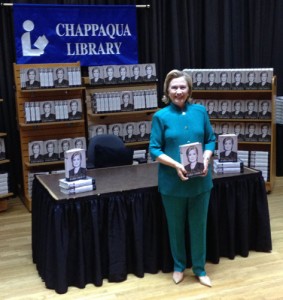 Secretary Hillary Clinton takes a few moments to pose, smile and wave to the press before sitting down to sign well over 1,000 books today.