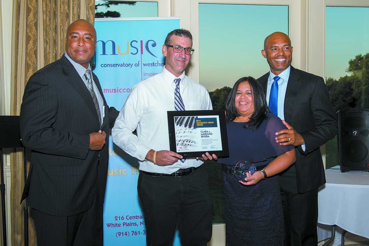 Rivera’s former teammate and musician, Bernie Williams (left) and Communications Director, Jon Chattman (center), present the Community Vision Award to Clara and Mariano Rivera.